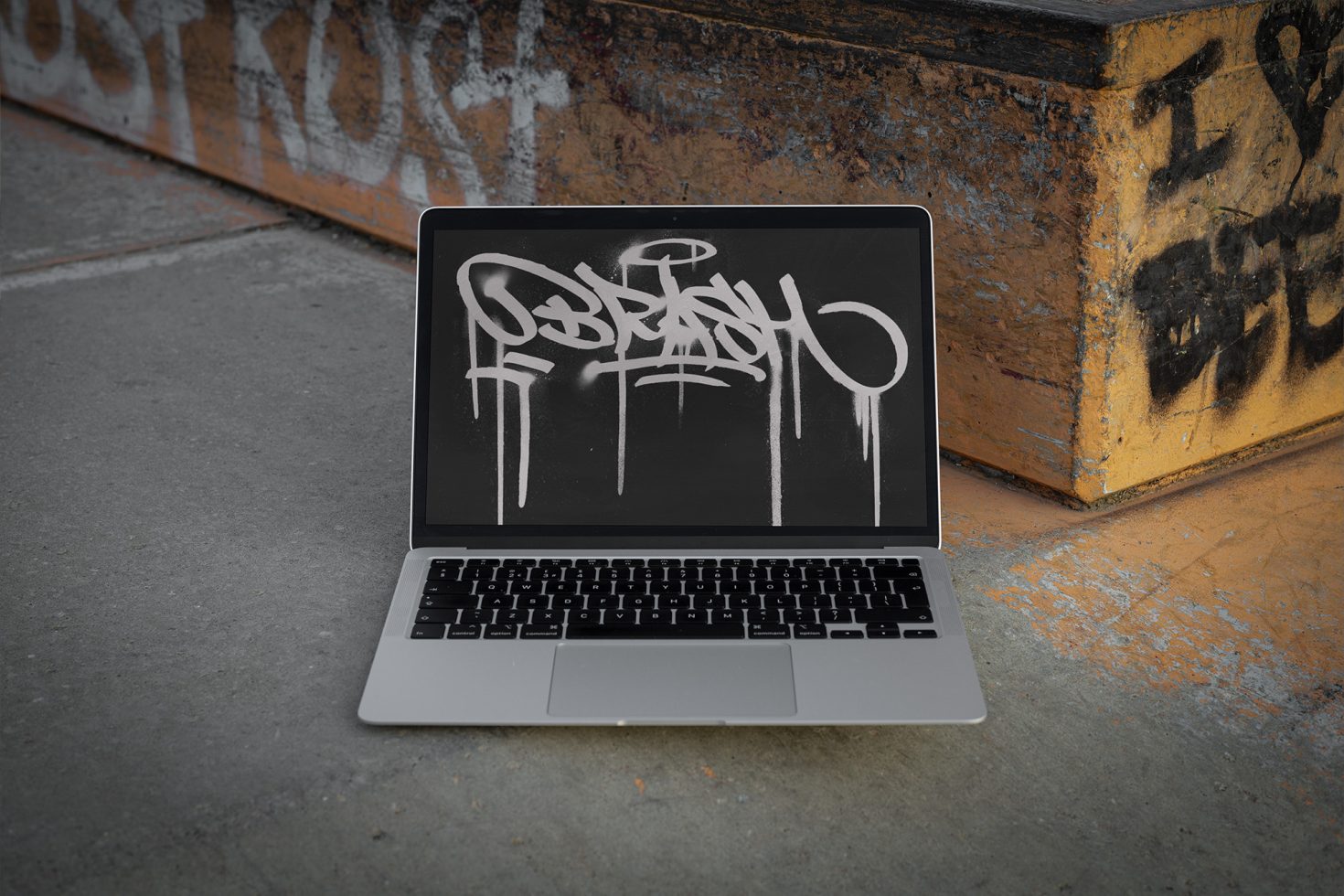 Laptop with graffiti style font on screen, urban setting, digital font mockup, street art, designer asset, template for presentations.